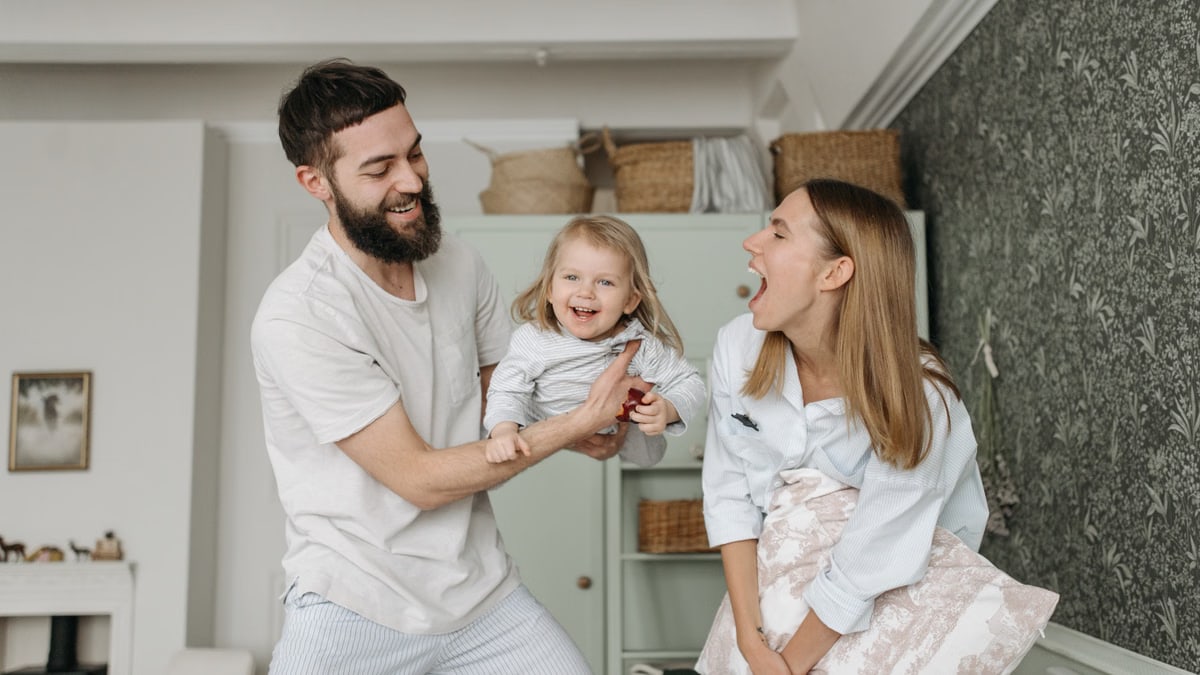 Joyful parents playing with their daughter at home, showcasing love and happiness.